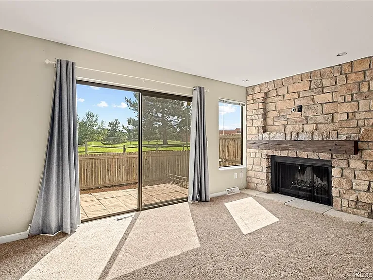 Living area with stone fireplace and sliding door to porch. Outlets above fireplace to mount TV. Porch looks out onto walking path and well-maintained green belt.