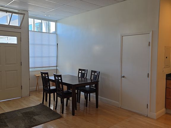 From kitchen toward dining table, front door, door to closet under stairs
