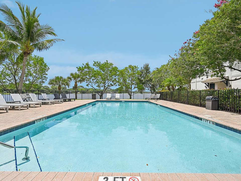 Inviting outdoor pool surrounded by lush palm trees and comfortable lounge chairs, perfect for relaxation and enjoyment.