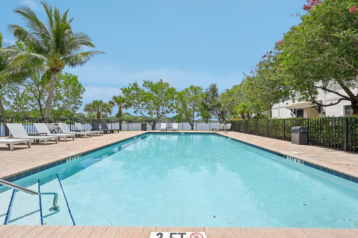 Inviting outdoor pool surrounded by lush palm trees and comfortable lounge chairs, perfect for relaxation and enjoyment.