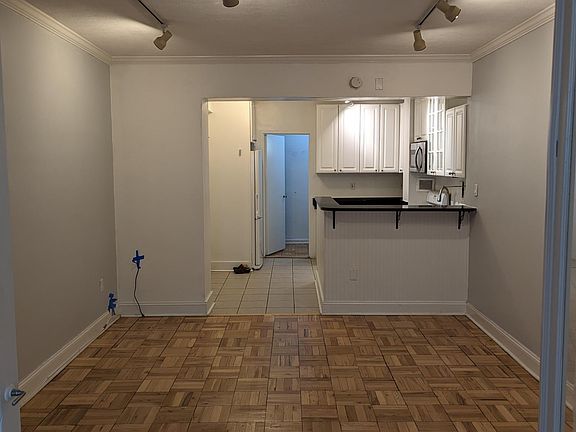 View from bedroom into living room, kitchen and hall into bathroom.