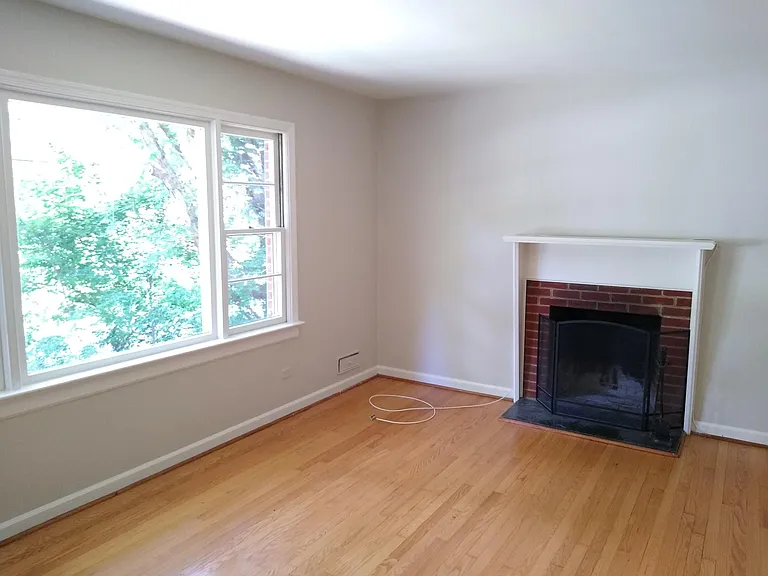 Living room, with fireplace and picture window, and a hardwood floor.