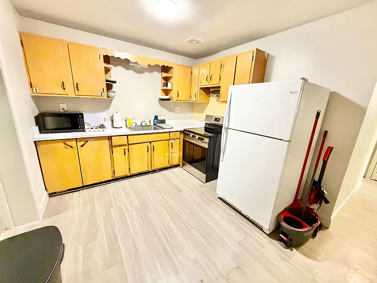 Shared kitchen with ample cabinet storage, generous counter space, and full-size appliances including range and refrigerator.
