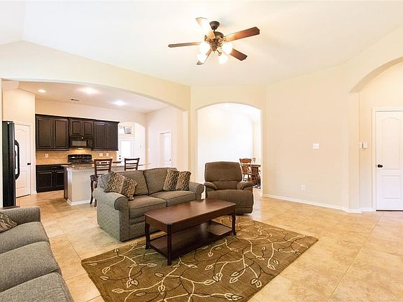 As you move further into the home you find this spacious family room featuring tile floors and a high ceiling.