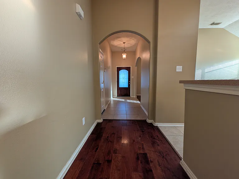A welcoming entrance featuring a gorgeous leaded-glass front door, elegant archways, tile entry, and rich hardwood flooring leading into the main living areas.