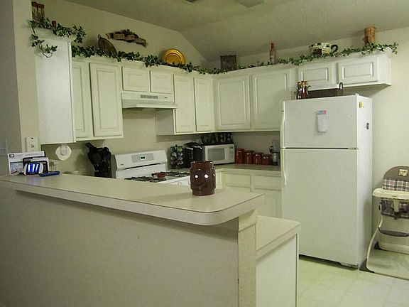 Kitchen has breakfast bar, numerous cabinets and overlooks the living area.
