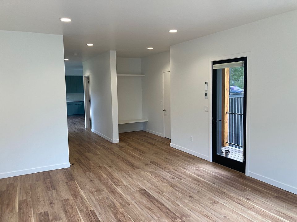 living room looking to front door (glass), garage door (white) and "mud room" area, doorway into 1/2 bath, and kitchen