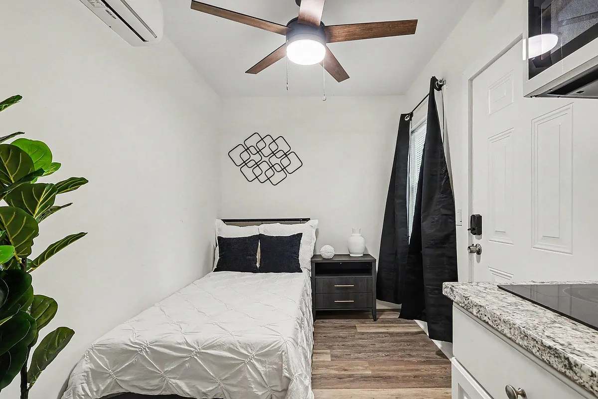 Well-appointed bedroom with ceiling fan, nightstand storage, and a window with blackout-style curtains for privacy. - Laurens Circle Sw A
