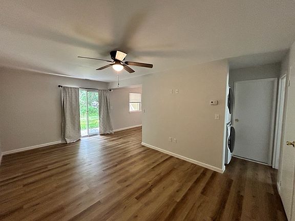 Looking from end of hallway into the condo to the sliding glass door and into the breakfast nook. Notice the new stackable washer and dryer on the left . Door on the right leads into the bathroom. Ceiling fan and light. Full wall is wired for flatscreen