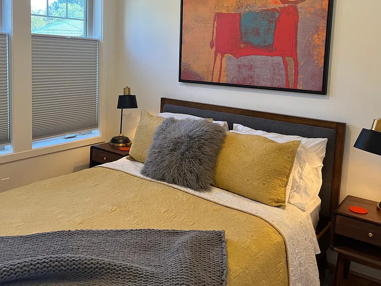 Queen bed with new organic Avocado mattress, bed tables with reading lamps and black out shades.