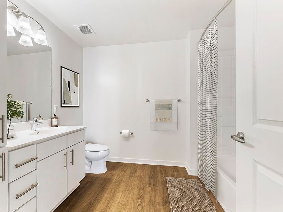 Renovated Package I bath with white laminate countertops, white cabinetry, and hard surface flooring