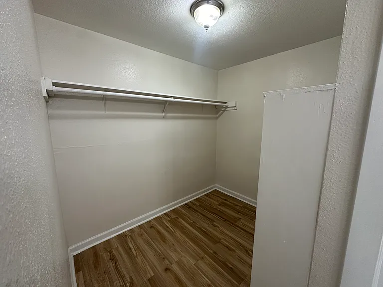 Spacious walk-in closet featuring modern lighting and elegant flooring. Spacious walk-in closet featuring modern lighting and elegant flooring.