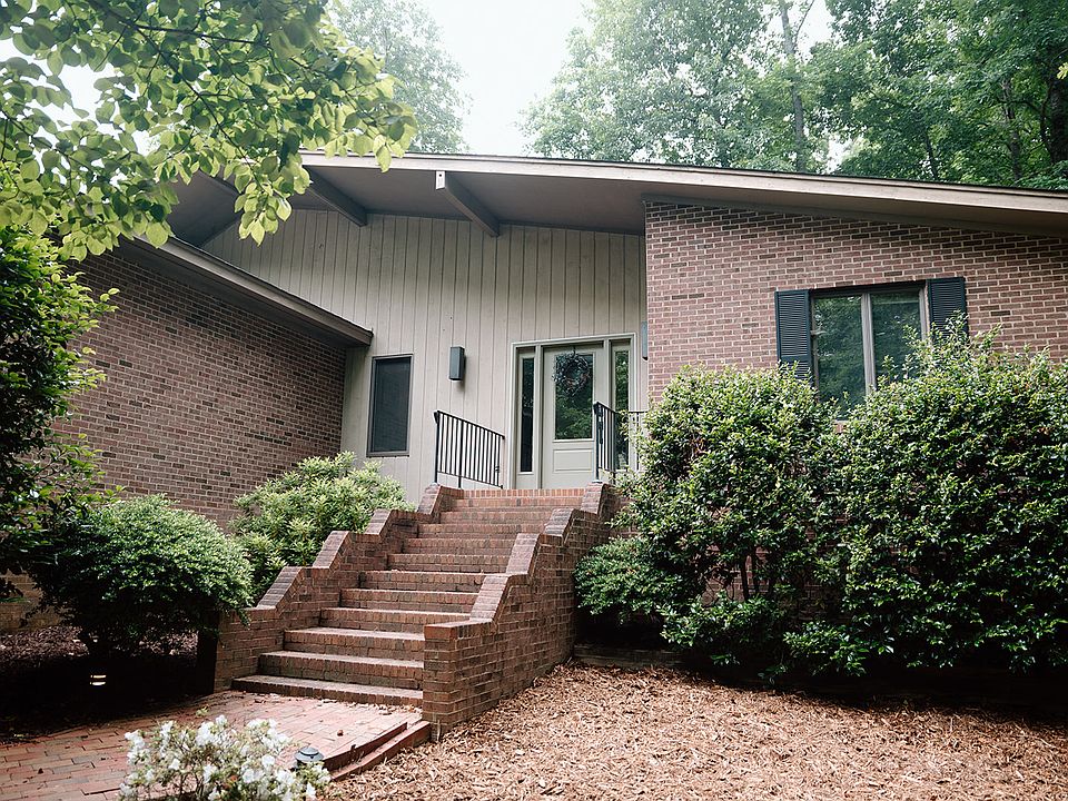 Mid Century Modern home with mature landscaping and a grand brick entryway.