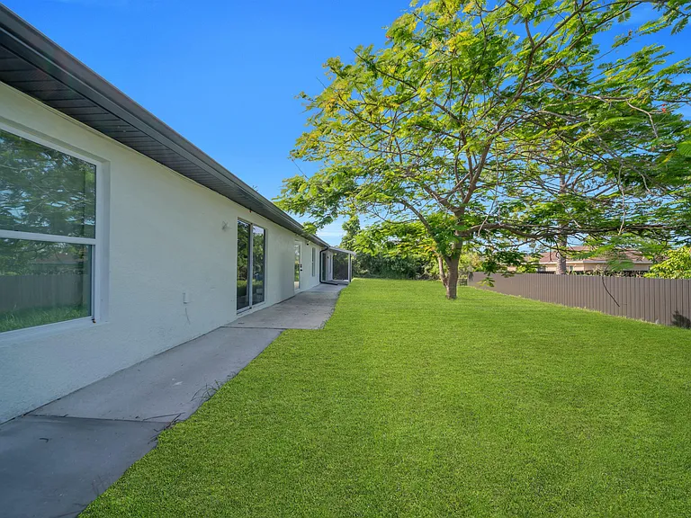 Spacious fenced backyard with a large shade tree and a concrete patio/walkwaygreat for outdoor dining and relaxing.