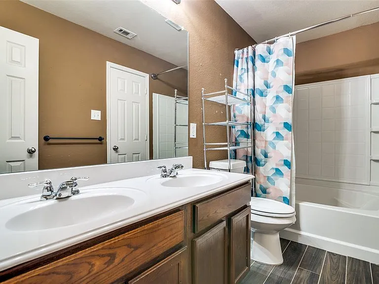 Full bathroom with toilet, hardwood / wood-style flooring, shower / tub combo, and double vanity