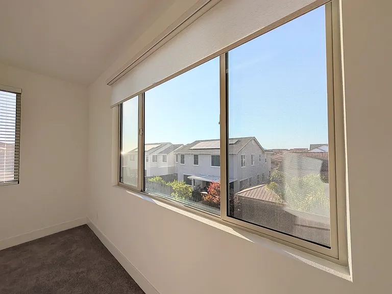 This versatile room showcases stunning, oversized panoramic windows that bring the outdoors in. Fitted with elegant light filtering roller shades, this airy space is ideal for a home office, gym, or lounge.