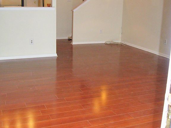 Beautiful laminate floor from front door into living room and eating area with kitchen to the left and view to the upstairs on the right.