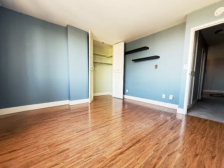 Spacious primary bedroom with hardwood floors and sweeping north-facing views of the Missouri River and CPKC Stadium