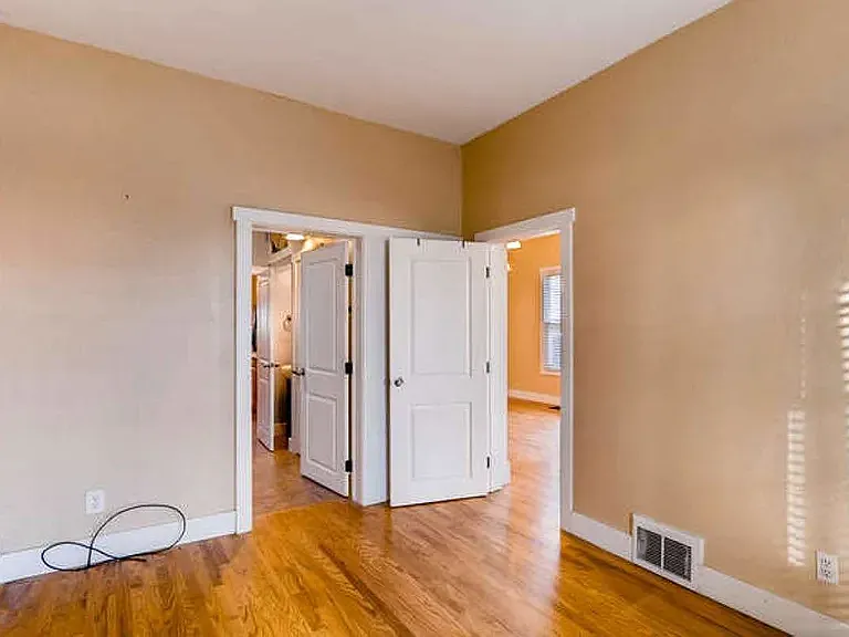 The primary bedroom enjoys warm hardwood floors and connects with the bathroom