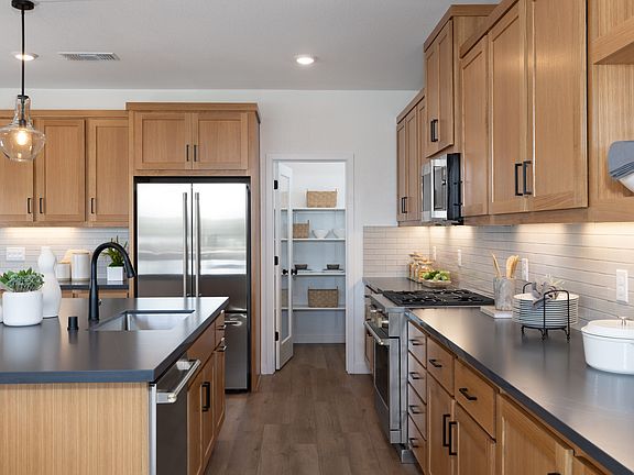 A modern and well-equipped kitchen with light wood cabinets, stainless steel appliances, and a sleek