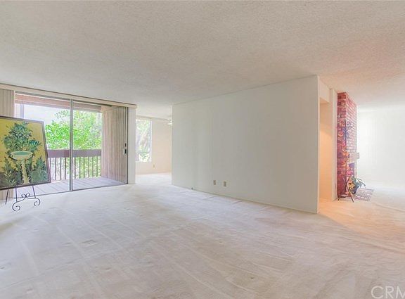 The bright and open living room is filled with natural light and the sounds of nature from the floor to ceiling sliding glass doors which lead to the balcony.