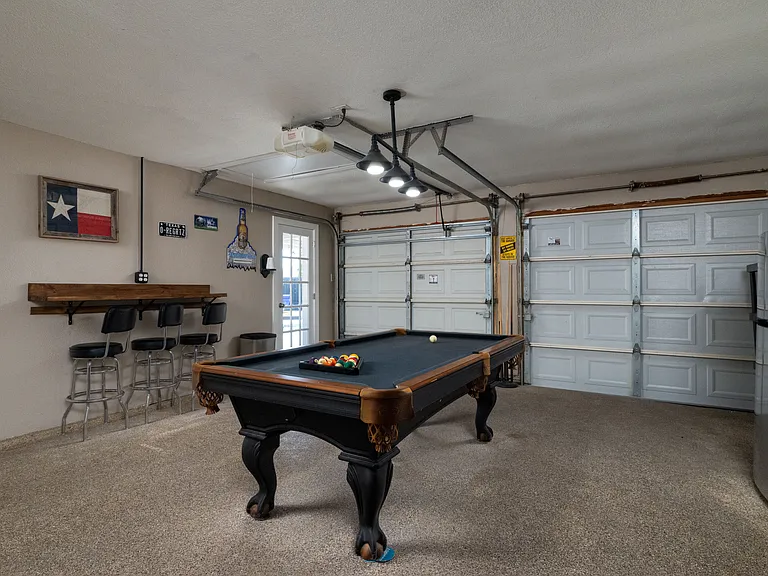 AMAZING game room featuring a pool table, fridge/freezer, full bar with bar tools & bar stools, 2 flat-screen Roku TVs, electronic bags game, darts, and air conditioning unit _ the perfect space to kick back, entertain, and make lasting memories.