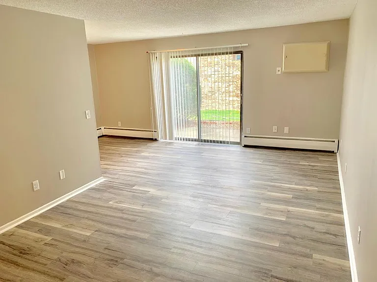 Large, bright living room, with air conditioner and walkout to exterior patio, attached dining room area.