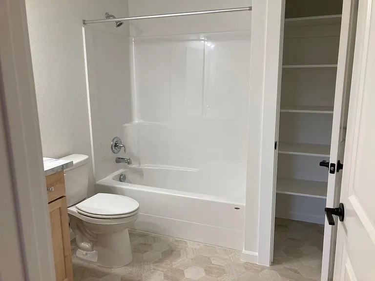 En suite full bath with linen closet storage.