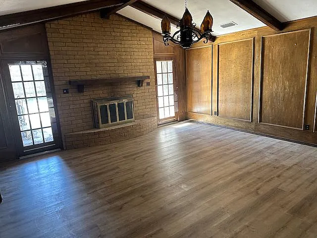 Custom wood paneled living room features ample natural light via windows and skylight. Propane fueled gas fireplace, Spanish light fixtures, built in desk and wet bar found in this spacious room.