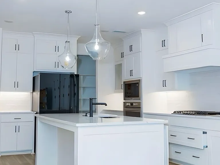 Kitchen featuring light wood finished floors, white cabinets, light countertops, a center island with sink, and tasteful backsplash