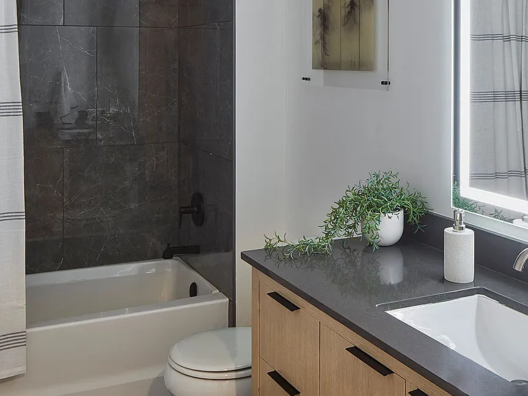 Apartment bathroom with wood-style flooring and LED vanity mirror.