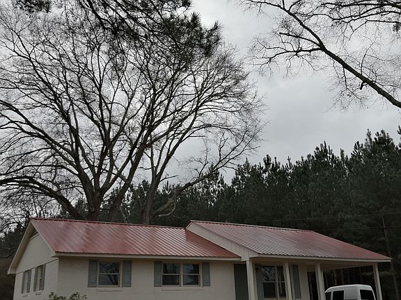 Four sides brick, metal roof, large shade trees.