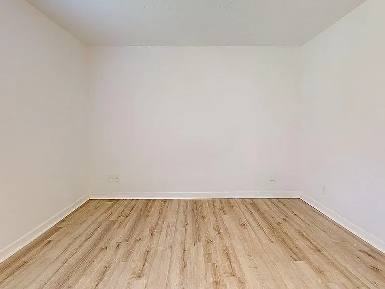 Bright and inviting empty room with elegant wood flooring and pristine white walls, perfect for personalized design.