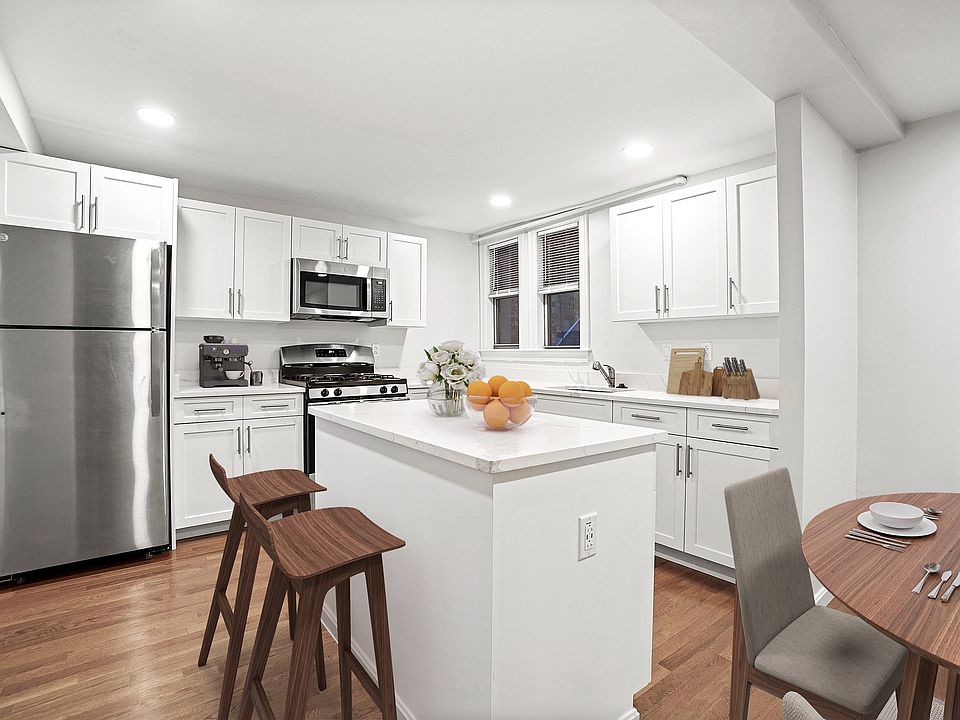 Modern kitchen with sleek stainless steel appliances, elegant white cabinetry, and a cozy breakfast nook with stylish seating.