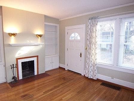 Living room with wood burning fireplace, built in storage and front door entrance onto Holly Street.