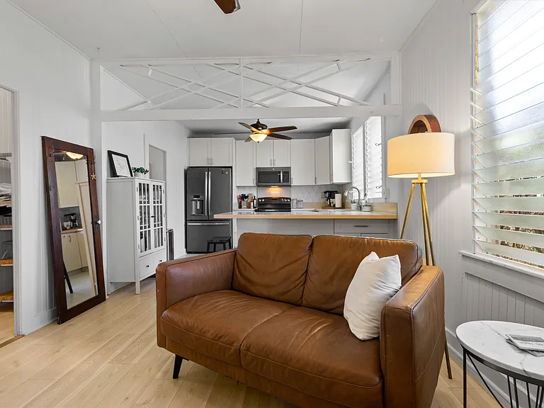 The living room includes an Italian leather sofa and loveseat and one chair, TV, ceiling fan, windows and an AC unit. The living room opens to the lanai and blends seamlessly with the kitchen.