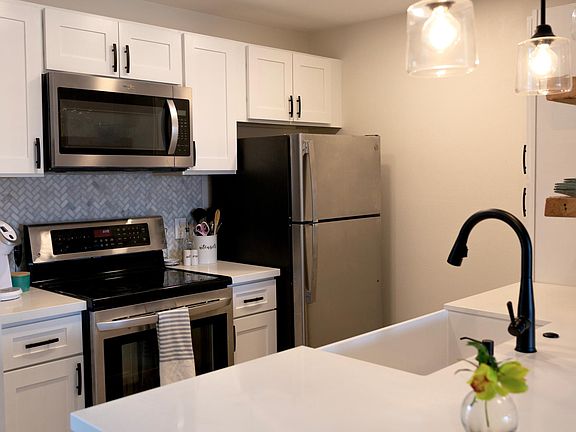 Kitchen with updated appliances and white granite countertops, touches sink and garbage disposal.