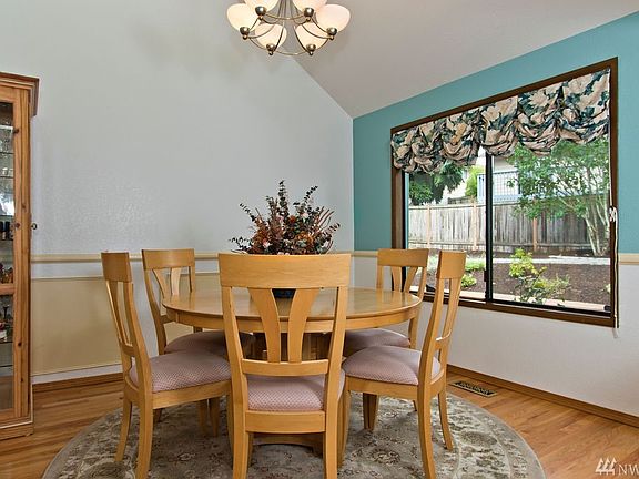 The formal dining room is open to the living room and also includes a tall angled ceiling that adds to the spaciousness of the heart of the home.  The family room and kitchen are located on the other side of the wall with the cream colored panels.  Already a timely floorplan for a home built in 1983, you could explore opening this cream wall more to the kitchen and family room, if preferred.