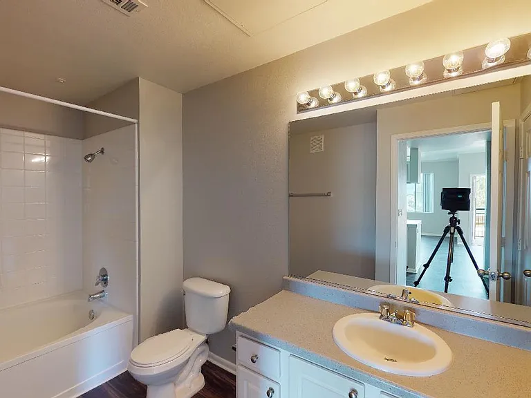 Apartment bathroom with large soaking tub and wood-style flooring.
