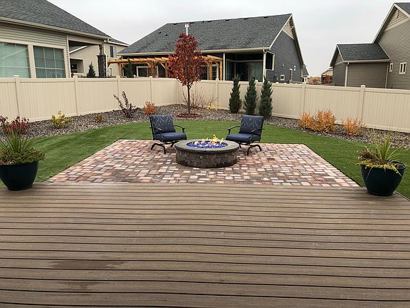 Large, xeriscaped backyard with gas fire pit and natural looking turf