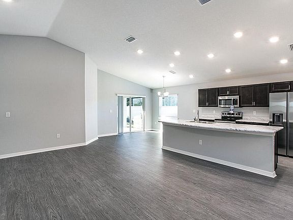 Open living flows under an airy volume ceiling with luxury vinyl plank flooring - Photo showcases a