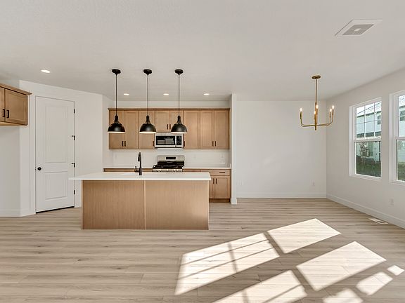 Modern kitchen with wooden cabinets, an island with pendant lights, and a chandelier in the adjacent