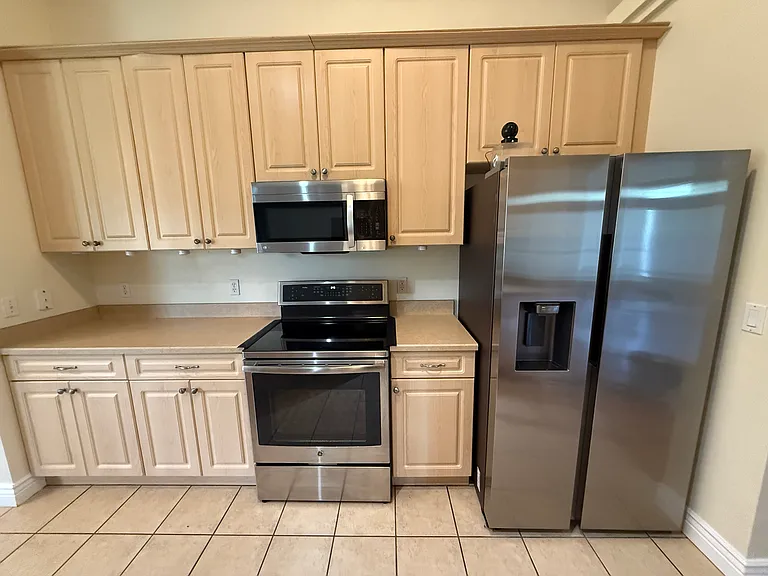 Stainless steel appliances include dishwasher, induction cooktop range, side by side refrigerator and mounted microwave