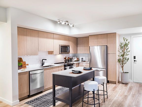Warm wood cabinetry, clean-lined finishes, and a functional island create a kitchen designed for everyday ease at Modera Aventura.