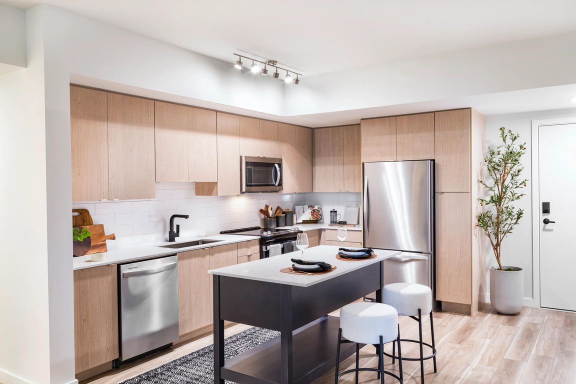 Warm wood cabinetry, clean-lined finishes, and a functional island create a kitchen designed for everyday ease at Modera Aventura.