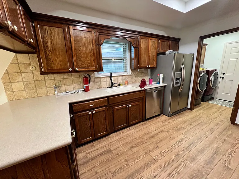 View of sink area with window over sink. New kitchen faucet and large sink with garbage disposal.