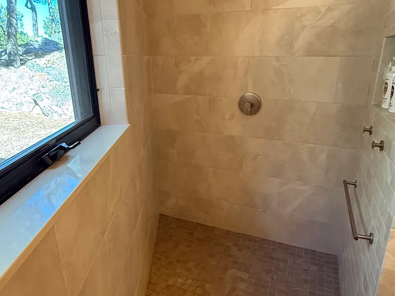 Master bath walk-in shower with view to junipers