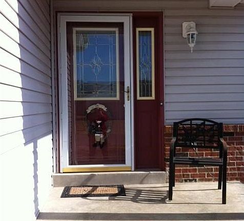 Front entry on covered porch with storm door, striking door and