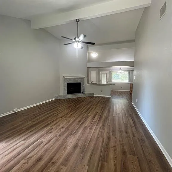Vaulted ceilings with, wood-finish flooring, a ceiling fan, and a fireplace with a tile finish surround