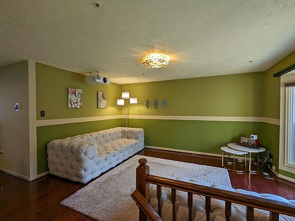 The living room with hardwood floors and HD projector. Furniture/carpet not included.